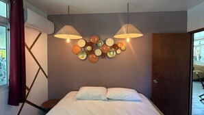 Un dormitorio con una cama, dos lámparas de pared, un adorno en la pared y una puerta.