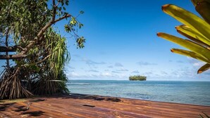 A wooden deck with a view of the sea and a small island in the distance. - Vahine Ori Lodge (Tumaraa)