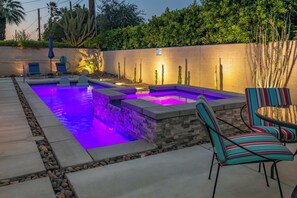 A swimming pool with a stone border and a stone wall in the background. - Desert Haven Hideaway - A Ryson Property (Palm Springs)