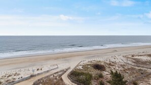 A beach with a sandy shore, a wooden fence, and a clear sky. - Sea Terrace 801 (Ocean City)