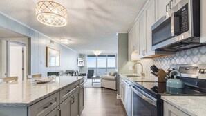 A modern kitchen with a large island, stainless steel appliances, and a view to the outside. - Sea Terrace 801 (Ocean City)