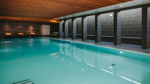 Ein Innenpool mit Holzbalkendecke und dunkel gefliesten Wänden.