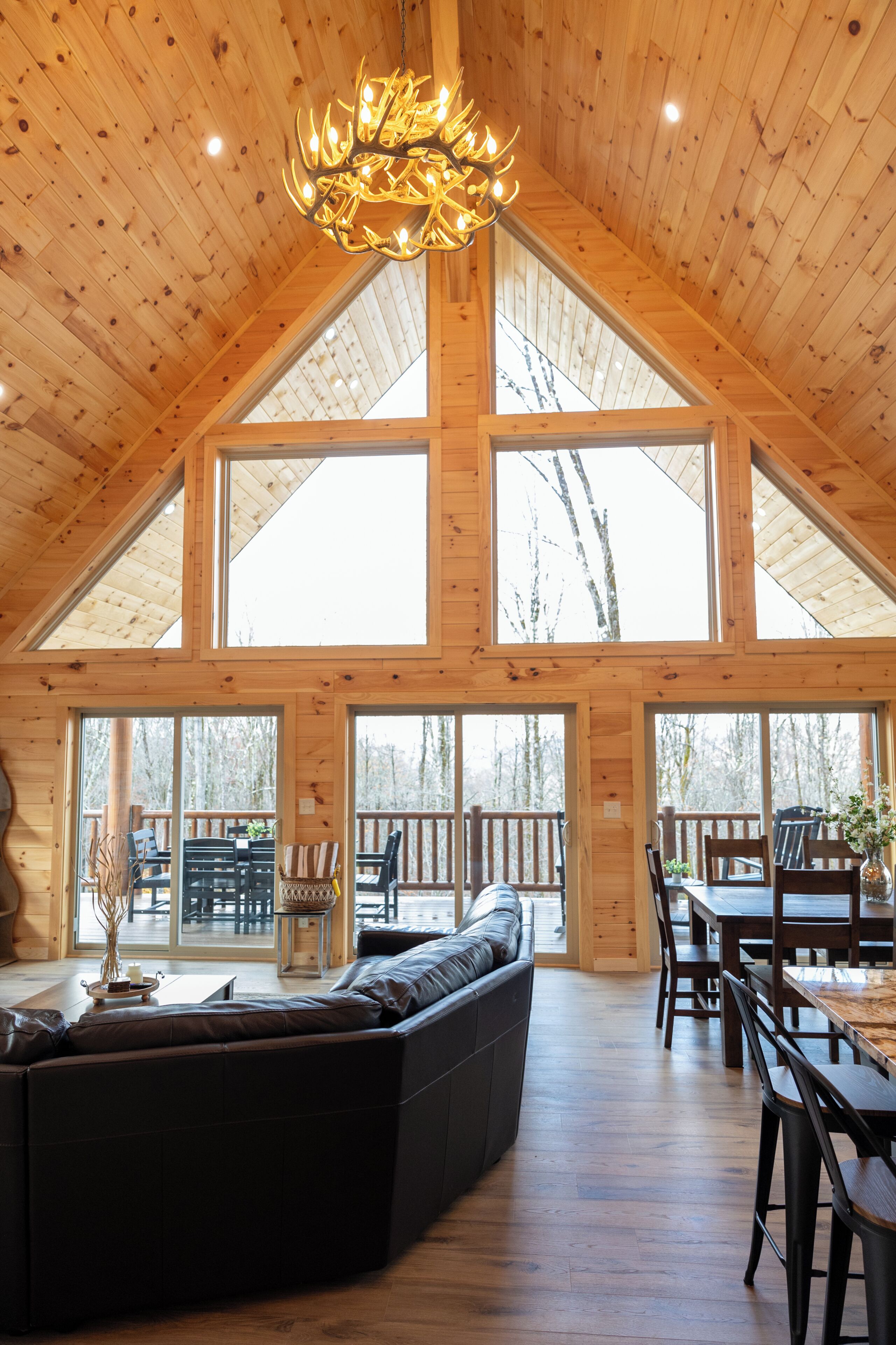 Sunlight pours through a dramatic wall of windows in the second-floor great room, framing peaceful views of the surrounding woods. Perched high above the ground, the space feels like a private treehouse—serene and perfectly connected to nature.