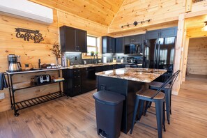Una cocina con paredes de madera, una isla central, taburetes de bar y una cafetera.
