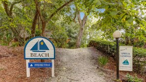 A sign indicating a beach area with owner bike storage and a welcome sign to Amelia Landings.
