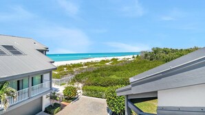 Une vue sur la côte, avec une plage, une maison dotée d’un balcon et un ciel dégagé.