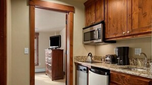A kitchen with wooden cabinets, a microwave, a coffee maker, and a dishwasher. - SKI-IN, SKI-OUT Breckenridge Bliss, 1-BR Luxury Resort w/Hot Tubs, Pool, Theater (Breckenridge)