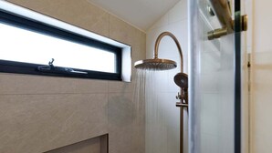 Un baño moderno con ducha, ventana y lavamanos.