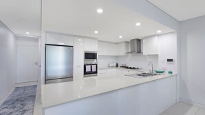 Ett modernt kök med en central köksö, inbyggda vitvaror och en stilren design.