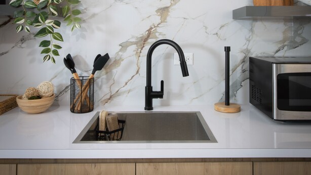 A kitchen with a marble backsplash, a black faucet, a microwave, and wooden cabinets. - Rubi Ocean House (Cabo Rojo)