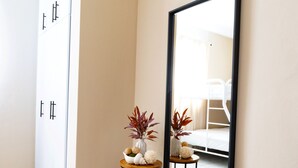 A hallway with a tiled floor, a bench, a small round table with decorative items, and a large mirror on the wall. - Rubi Ocean House (Cabo Rojo)