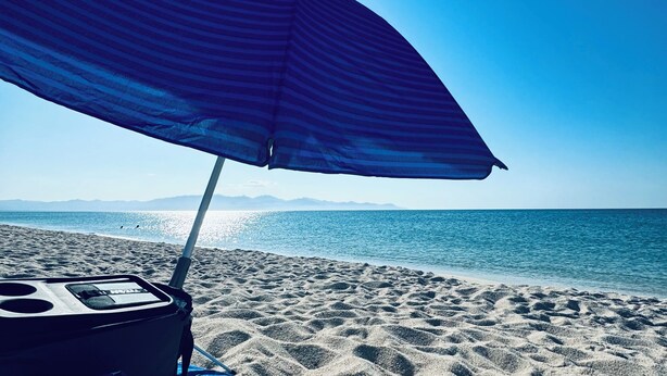 Une scène de plage avec un parasol rayé et une chaise de plage.