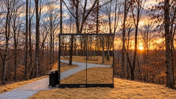 Un parco con un vialetto lastricato, una panchina di legno e un cestino.
