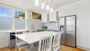 A modern kitchen with a central island, white cabinetry, stainless steel appliances, and pendant lighting. - Oceanfront Stay Steps to the Sand (The Entrance)