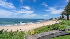 A beach with a warning sign, ocean waves, and a clear sky. - Oceanfront Stay Steps to the Sand (The Entrance)