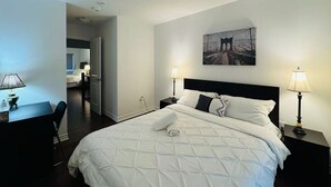 Camera d'albergo con un letto grande, due abat-jour, un quadro appeso al muro e una scrivania con lampada.