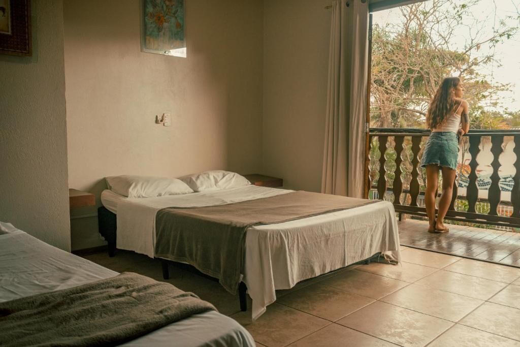 Un dormitorio con dos camas, un balcón y vistas a árboles.