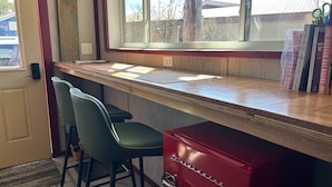 A kitchen area with a wooden countertop, two bar stools, a red appliance labeled 'Cuisinart', and a window with a view of the outside.