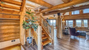 Ein Holzinnenraum mit Treppe, Essbereich und Blick durch große Fenster.