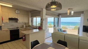 A modern kitchen with a dining area, a sofa, and a view of the ocean. - Oceanfront and beach views (The Entrance)