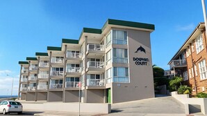 En bygning med flere etager, altaner, en delfin-logo og teksten 'Dolphin Court' på facaden.