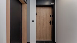 A modern elevator with a wooden door and black walls, featuring the number 533. - Cracow Novum Apartment #533 (Kraków)