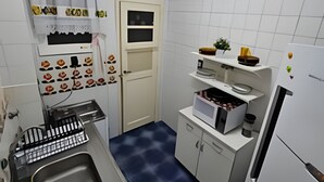 A compact kitchen with white cabinets, a stainless steel sink, a microwave, and a refrigerator. - 3 Minutos da Praia - Prime Location (Rio de Janeiro)