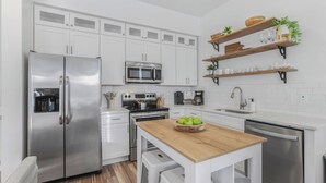 A modern kitchen with white cabinets, stainless steel appliances, a wooden island, and a built-in dishwasher. - New! Coastal House, Steps to Beach, Pool, Great Location! (Gulf Shores)