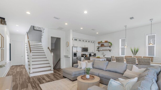 A modern living room with a grey sectional sofa, a wooden coffee table, and a staircase leading to the kitchen. - New! Coastal House, Steps to Beach, Pool, Great Location! (Gulf Shores)