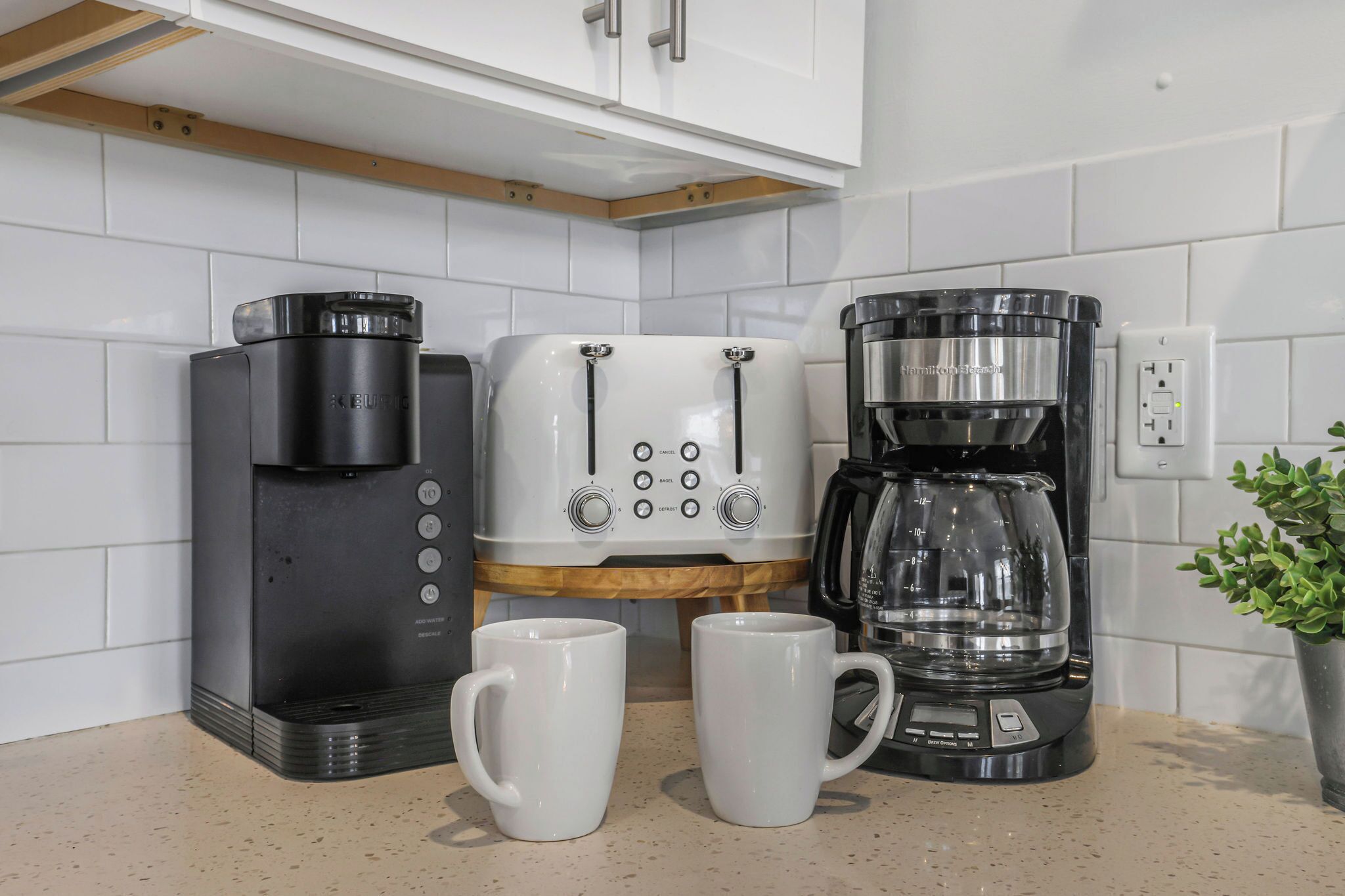 Eine Küche mit Kaffeemaschine, Toaster und zwei weißen Tassen auf der Arbeitsfläche.