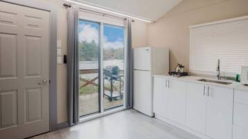 Een koelkast, een magnetron, een kookplaat, kookgerei, borden en bestek