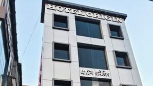 A modern hotel building with a sign reading "HOTEL ORIGIN" and another sign in a different language. - Hotel Origin (Guwahati)