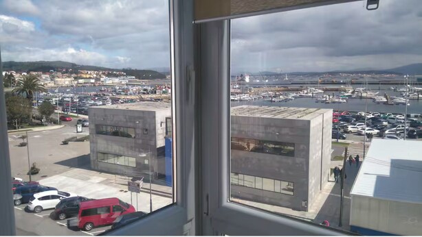 A view from a window overlooking a marina with boats, a parking lot, and buildings. - The house of Maria a Bazarra, 3. Sea views, elevator and air conditioning. (A Pobra do Caramiñal)