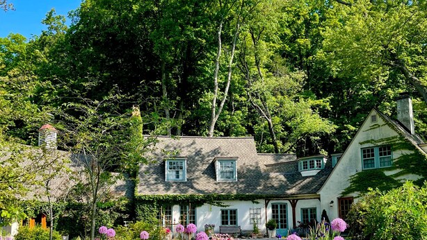 Ein Haus mit Garten, Teich und Bank.