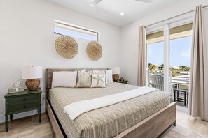 Ein Schlafzimmer mit einem großen Bett, zwei Nachttischen, einem Fenster und einem Balkon mit Blick.