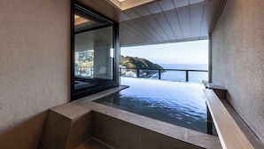 Un intérieur moderne avec une grande fenêtre donnant sur une étendue d’eau et une côte lointaine.