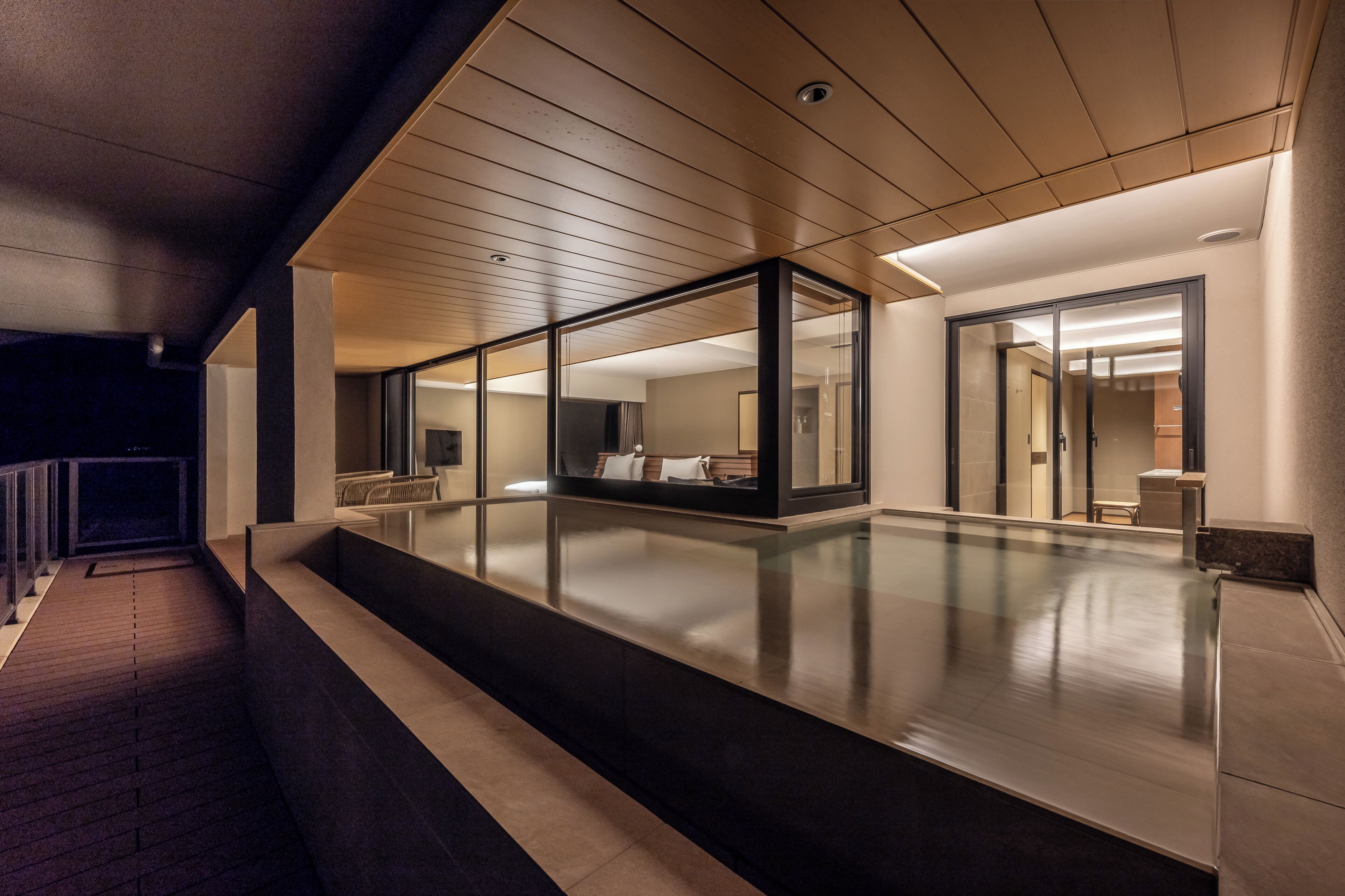 A modern hotel corridor with glass walls, a wooden ceiling, and a long, reflective floor.