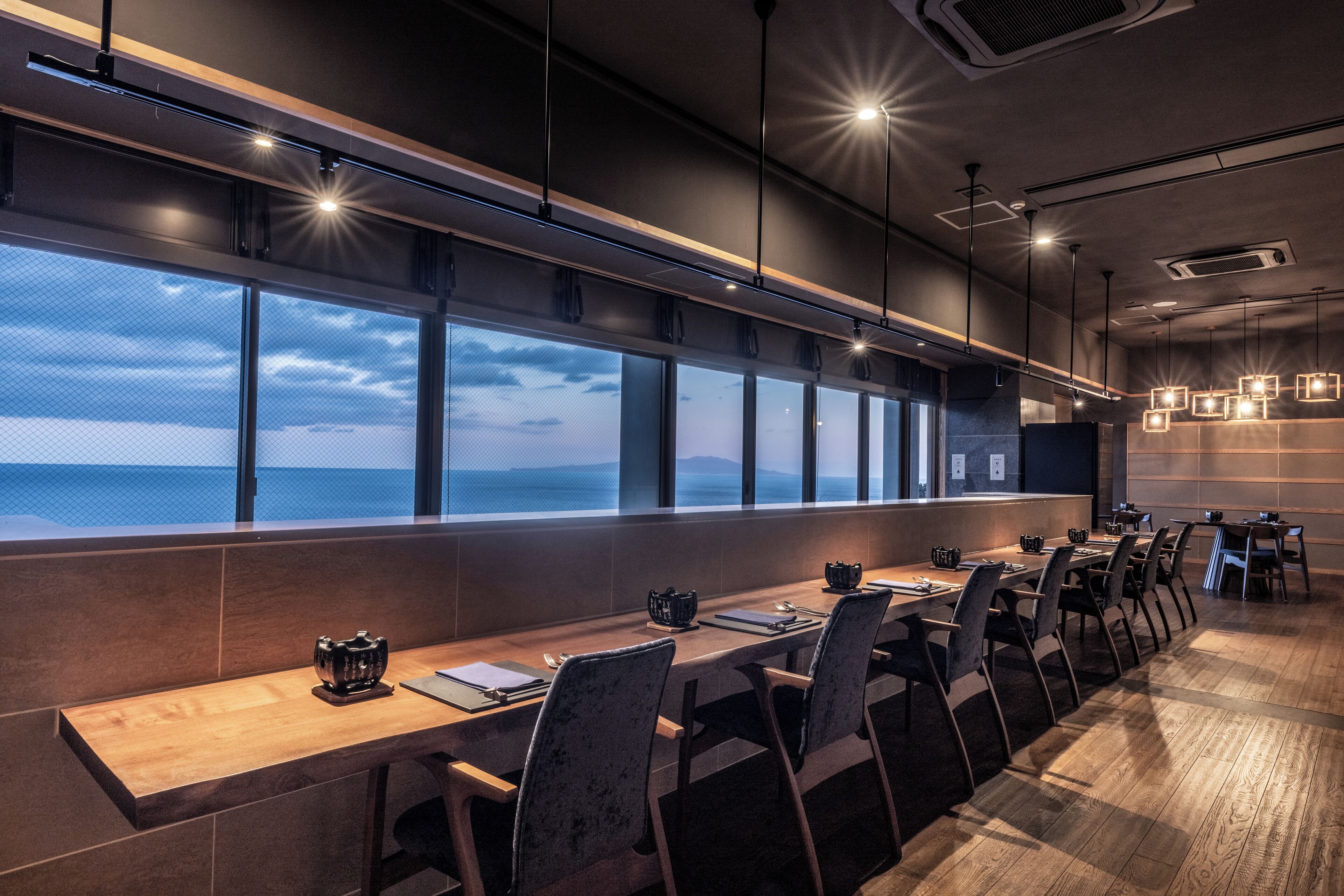 A conference room with a long table, chairs, and large windows overlooking a scenic view.