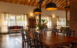 A spacious dining area with a wooden table and chairs, surrounded by large windows and a high ceiling with exposed beams. - Sevena Villa: Magical Home with a Yoga Shala (Weligama)