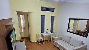 Ein Zimmer mit einem weißen Sofa, einem kleinen Tisch, einem Deckenventilator und einem Spiegel an der Wand.