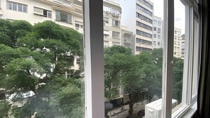 Blick durch ein Fenster auf ein Wohngebiet mit mehrstöckigen Gebäuden, Bäumen und geparkten Autos.