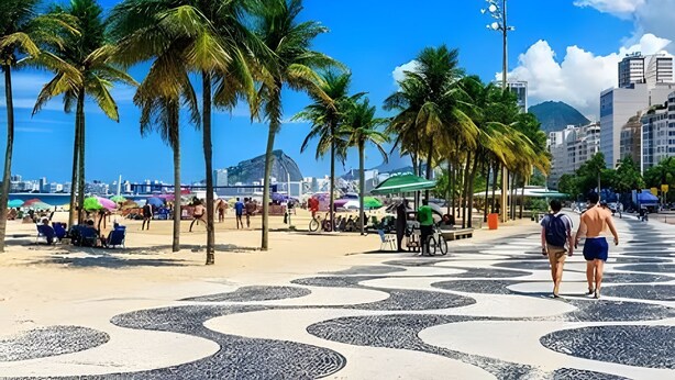 Eine Strandpromenade mit Palmen, einem gemusterten Gehweg und einer Stadtlandschaft im Hintergrund.
