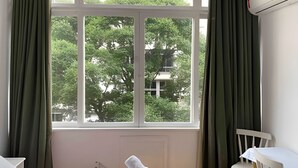 Ein Zimmer mit großem Fenster, weißer Heizung, weißem Stuhl und kleinem Tisch.