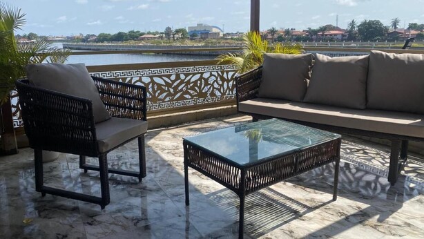 A terrace with a sofa, two chairs, and a glass coffee table. - Relax By Water-View 1-Bed-APT  With 24HRS PWR+ Wi-Fi (Lagos)