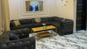 A modern living room with a sectional sofa, a coffee table, and a decorative mirror. - Relax By Water-View 1-Bed-APT  With 24HRS PWR+ Wi-Fi (Lagos)