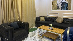 A living room with a black sofa, a black armchair, a wooden coffee table, and a large mirror on the wall. - Relax By Water-View 1-Bed-APT  With 24HRS PWR+ Wi-Fi (Lagos)