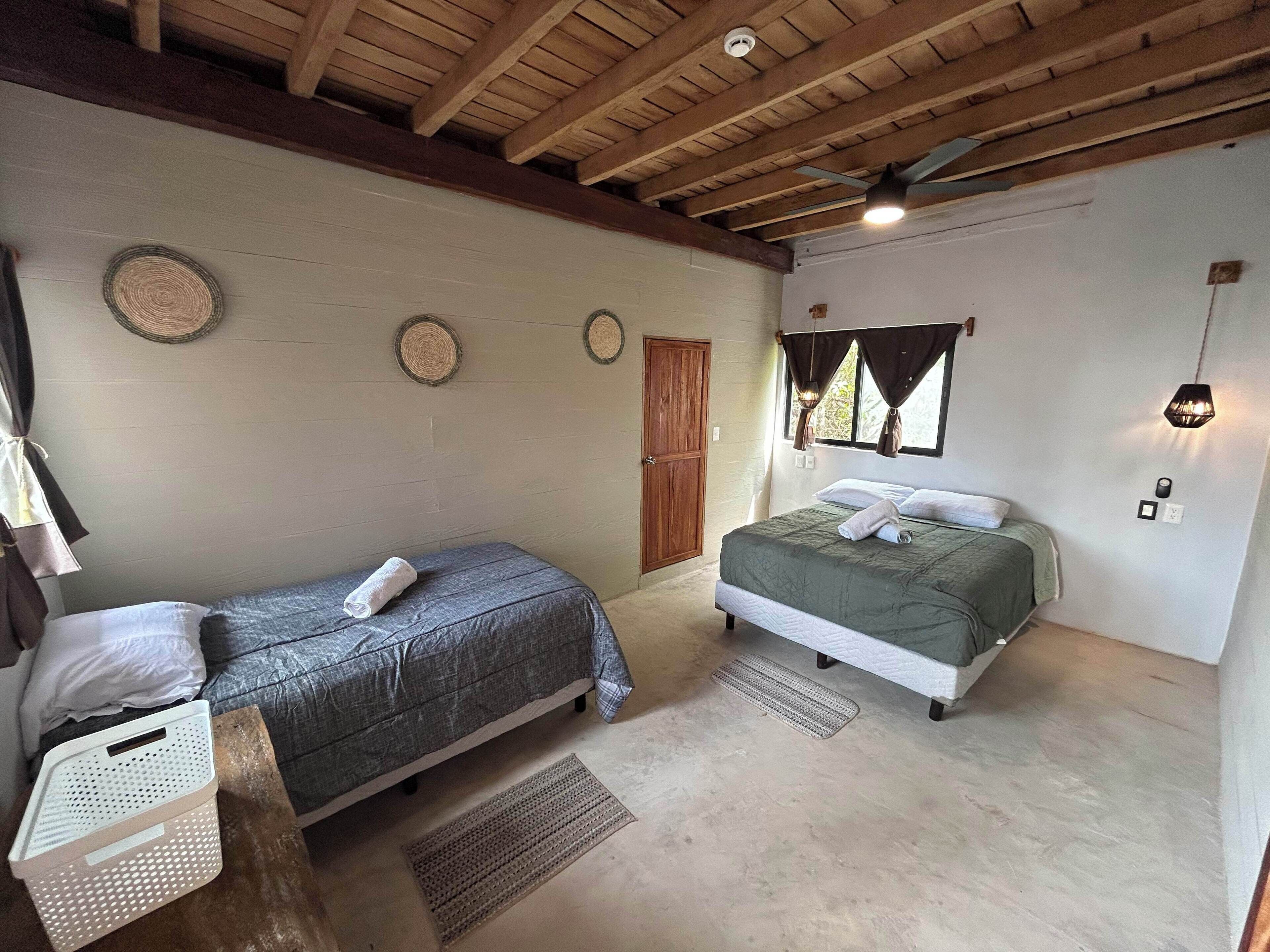 Ein Schlafzimmer mit zwei Betten, einer Holzbalkendecke und einem kleinen Tisch mit einem Korb.