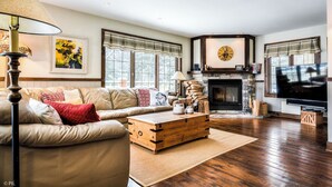 Un salon comprenant un canapé, une table basse en bois, une cheminée et un téléviseur.