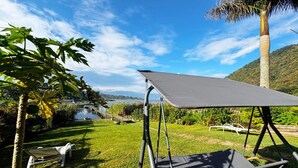 A hammock with a canopy in a grassy area with a lake and mountains in the background.