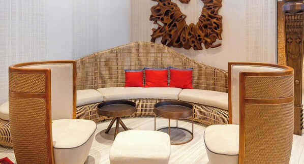 Ein modernes Wohnzimmer mit einer gebogenen Couch, zwei runden Couchtischen und Korbstühlen.